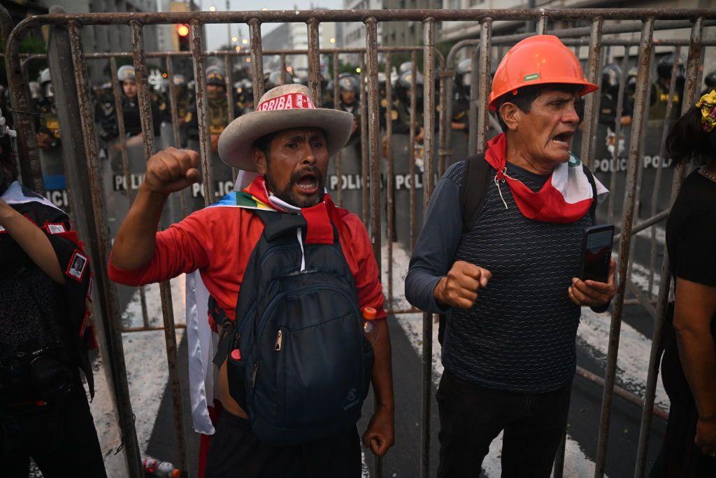 Dos personas gritan junto a una valla colocada por la Polic&iacute;a en el centro de Lima. 