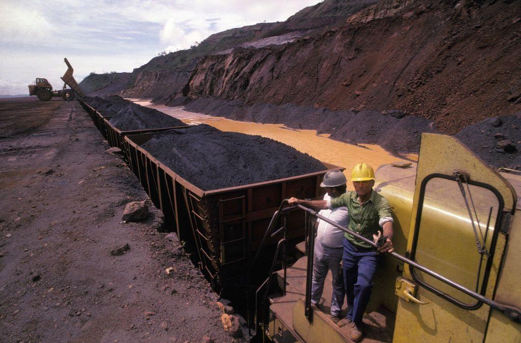 Unos trabajadores venezolanos en un tren cargado de mineral de hierro en el estado Bol&iacute;var.