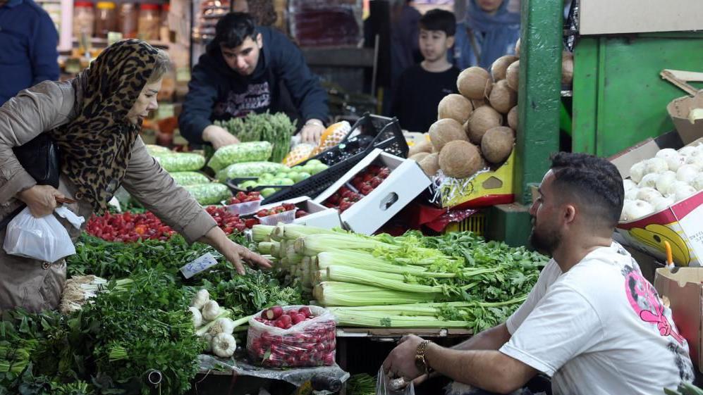 Una mujer compra vegetales en el mercado 