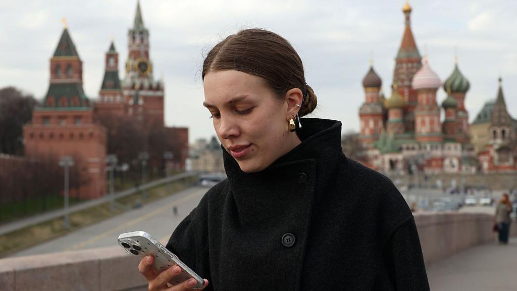 Una mujer usa su tel&eacute;fono cerca del Kremlin.