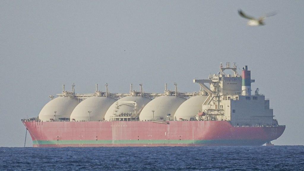 Un gigantesco buque cisterna rojo, con cinco enormes c&uacute;pulas blancas, se aleja de la c&aacute;mara.