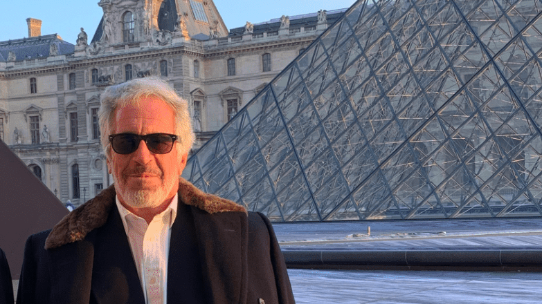Jeffrey Epstein, con barba gris, abrigo y gafas de sol, posa frente al Museo del Louvre y su pir&aacute;mide de cristal.