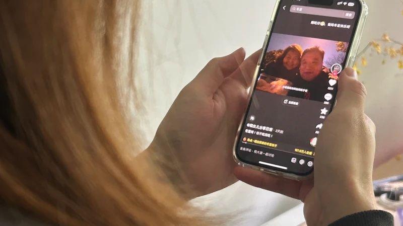 Una mujer mira a Pan y Zhang en su tel&eacute;fono.