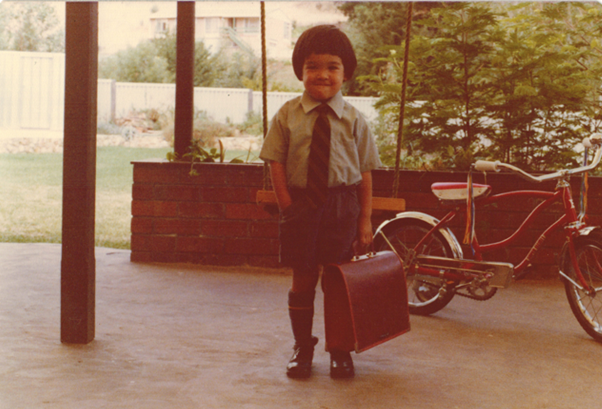Terence Tao vestido con el uniforme escolar y un malet&iacute;n sonr&iacute;e a la c&aacute;mara