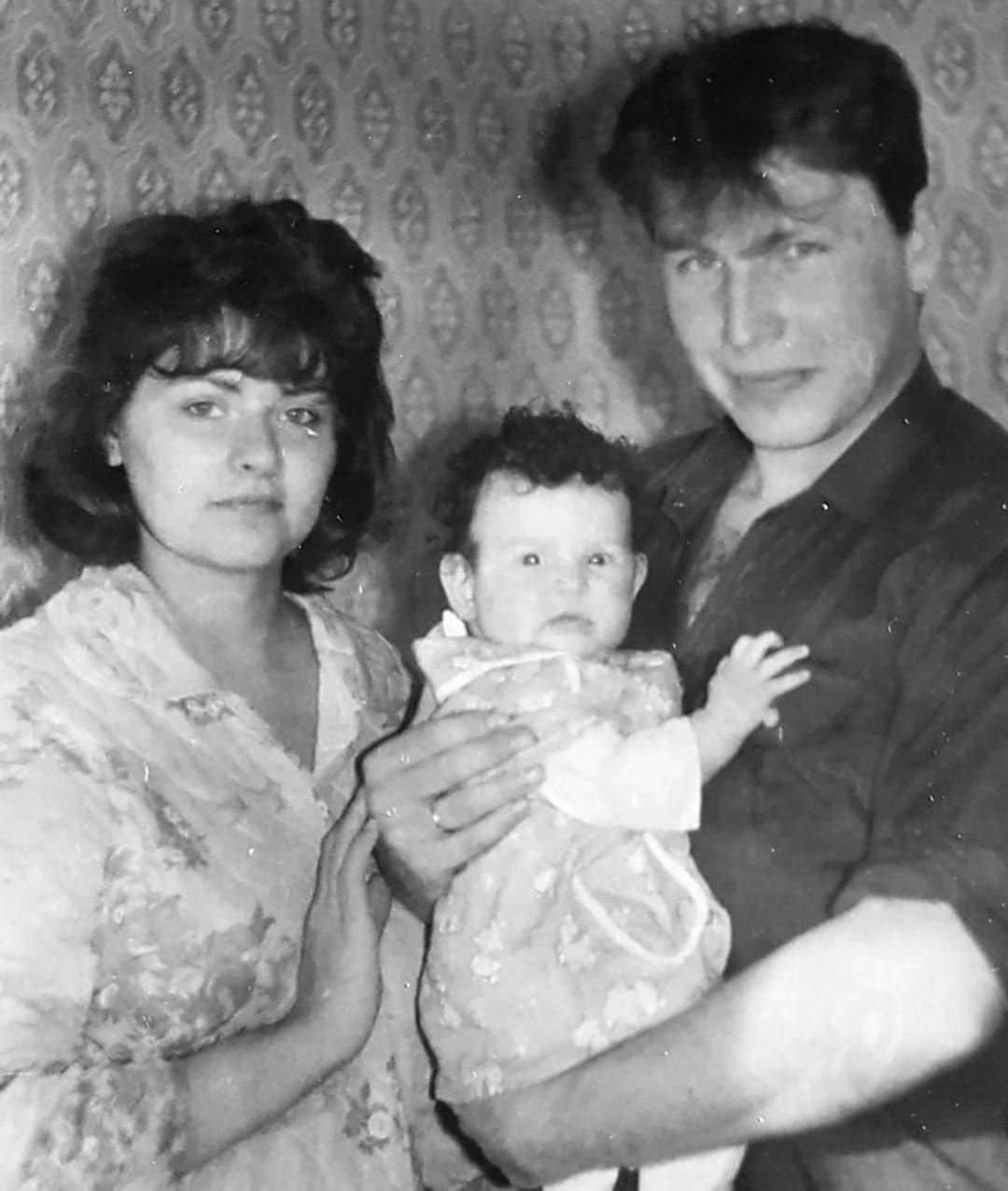 Fotograf&iacute;a en blanco y negro de Iryna y Serhiy con la peque&ntilde;a Katya. Serhiy lleva una camisa oscura y sostiene a la ni&ntilde;a, que tiene el pelo oscuro y mira a la c&aacute;mara. Iryna lleva una blusa de flores.