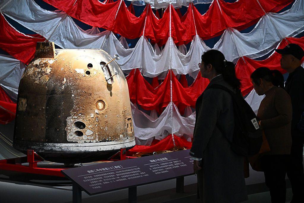 Unas personas ven la c&aacute;psula Chang'e 6 en una exposici&oacute;n