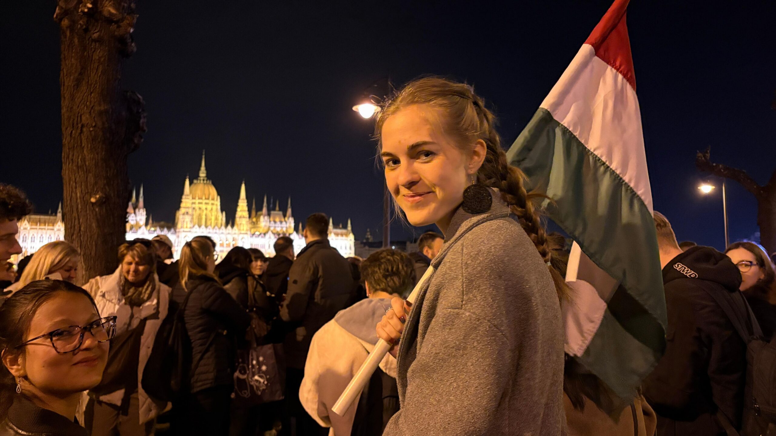 Una joven con el pelo largo trenzado sostiene una bandera de Hungr&iacute;a durante las celebraciones frente al parlamento nacional, a orillas del r&iacute;o Danubio.