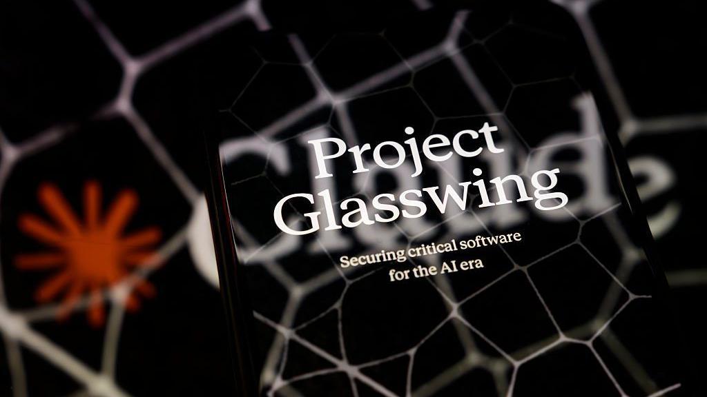 La imagen promocional del Proyecto Glasswing se muestra en la pantalla de un tel&eacute;fono inteligente colocado sobre una superficie reflectante sobre la cual se proyecta un logotipo de Claude con patrones hexagonales, en Cr&eacute;teil, Francia, el 8 de abril de 2026.