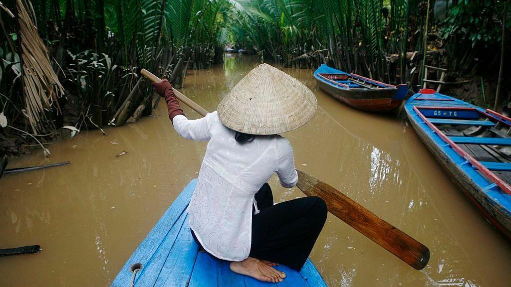 Una mujer vietnamita navega en su bote por un peque&ntilde;o afluente del r&iacute;o Tien en My Tho.