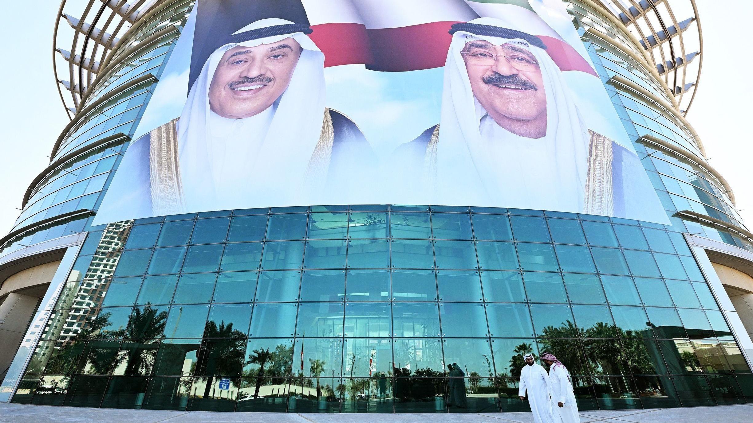 Ciudadanos kuwait&iacute;es pasan frente a grandes retratos del emir de Kuwait, el jeque Mishal al &Aacute;hmad al Y&aacute;ber al Sabah, y del pr&iacute;ncipe heredero, el jeque Sabah al Jalid al Sabah, exhibidos en la fachada del Instituto de Diabetes Dasman en Ciudad de Kuwait el 10 de marzo de 2026.