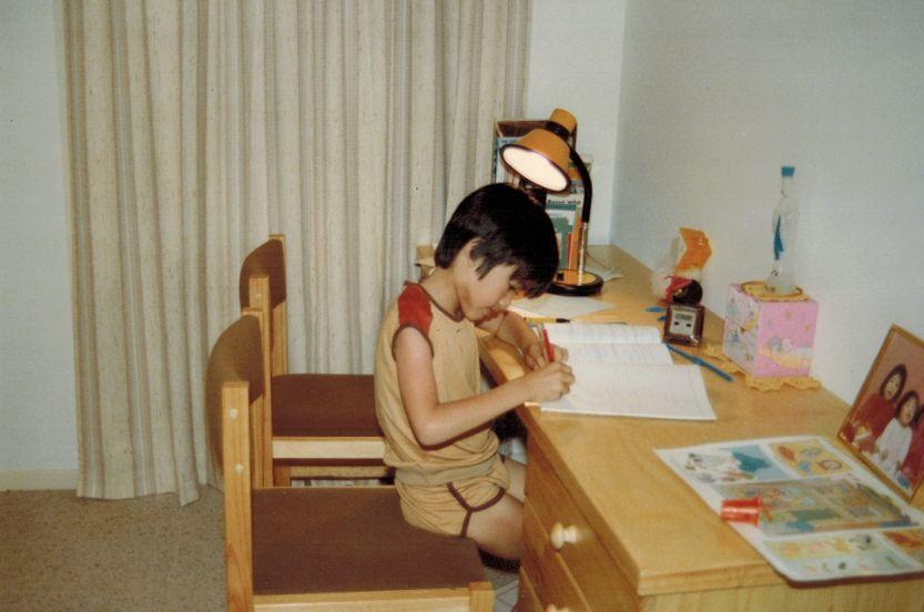 Terence Tao sentado en un escritorio escribiendo sobre un cuaderno