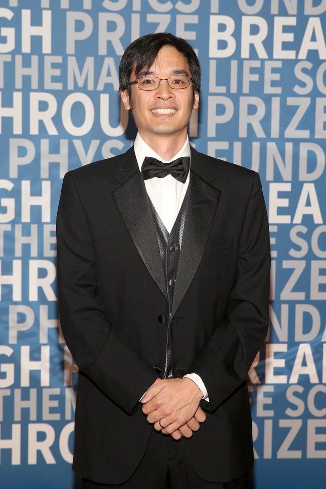 Terence Tao sonr&iacute;e a la c&aacute;mara. Est&aacute; vestido con un elegante traje negro y corbat&iacute;n.