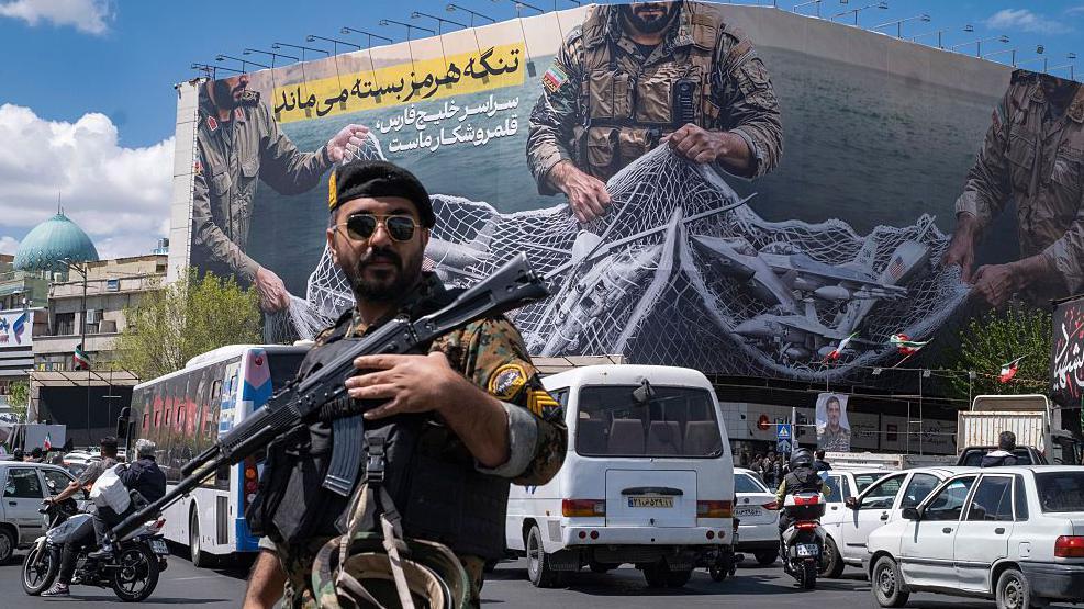 Un soldado iran&iacute; y detr&aacute;s una pancarta sobre el estrecho de Ormuz