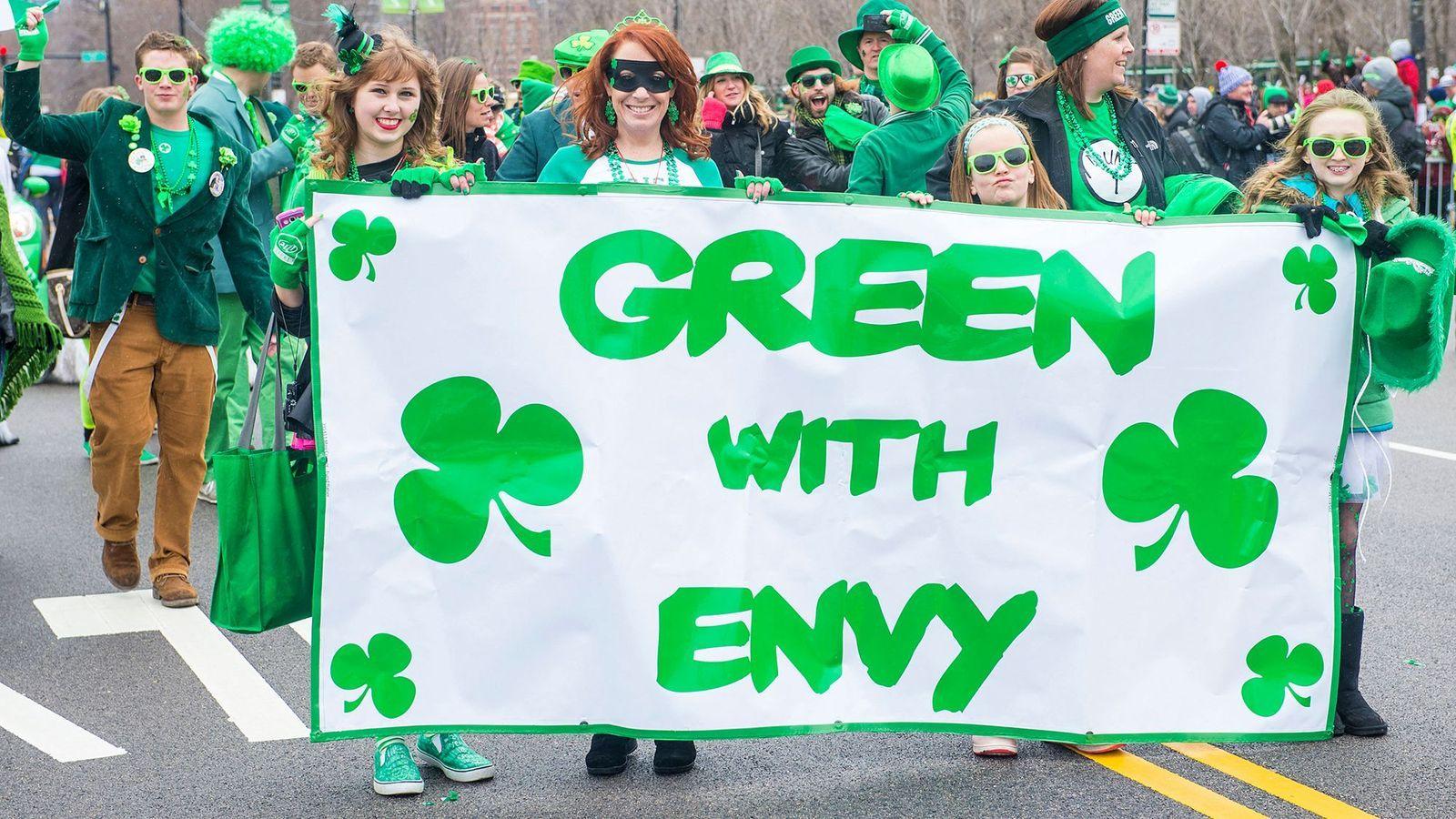 Gente marchando con un cartel que dice Green with Envy (Verde de envidia)