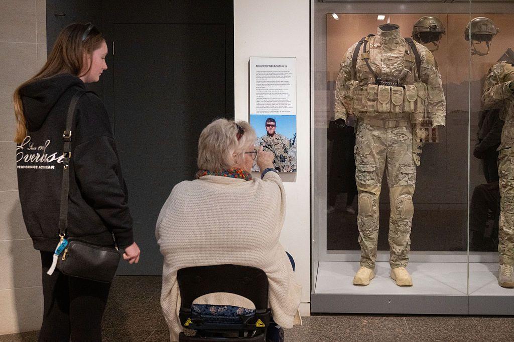 Una se&ntilde;ora en silla de ruedas junto a otra m&aacute;s joven ven uno de los uniformes de Roberts-Smith en el Museo de la Guerra de Australia.