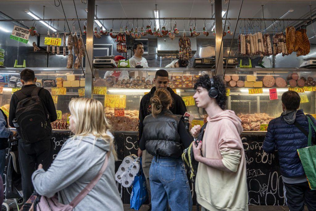 Personas frente a un puesto de carnes y quesos en Uruguay.
