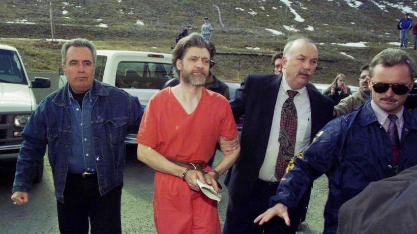 Momento del traslado del Unabomber, vestido con traje naranja, rodeado por agentes federales en abril de 1996.