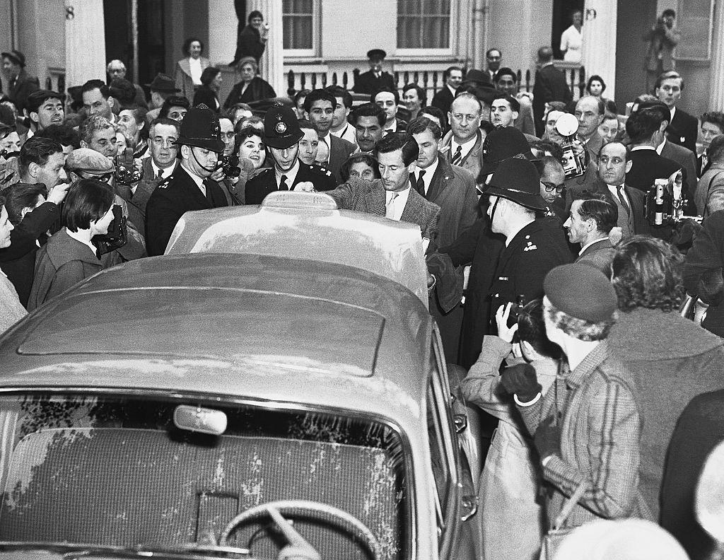 Un hombre abre el ba&uacute;l de un autom&oacute;vil, mientras est&aacute; rodeado por varios polic&iacute;as londinenses y una gran cantidad de periodistas y curiososos tomando fotograf&iacute;as.