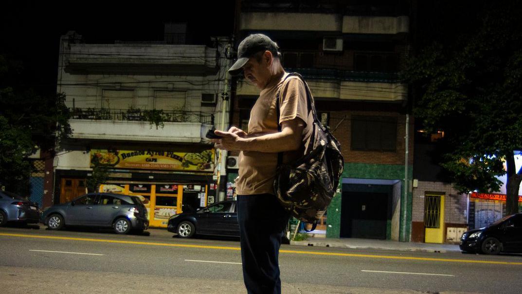 Un hombre con una mochila esperando el bus en Buenos Aires. 