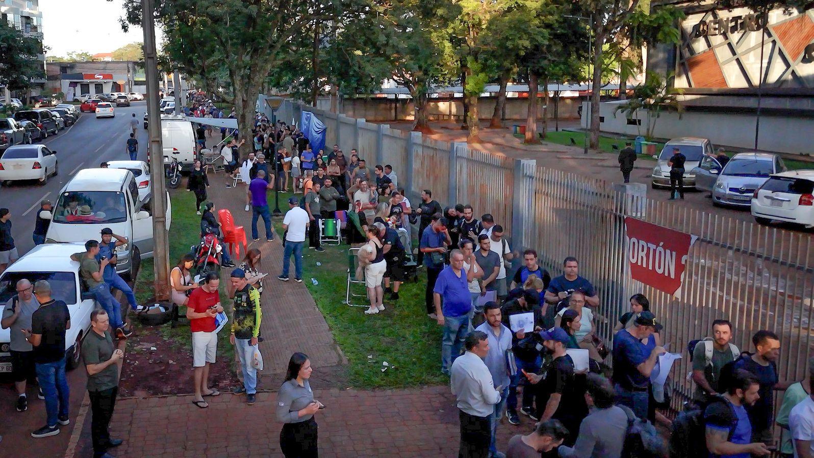 Vista a&eacute;rea de una larga fila de personas frente a un edificio p&uacute;blico.