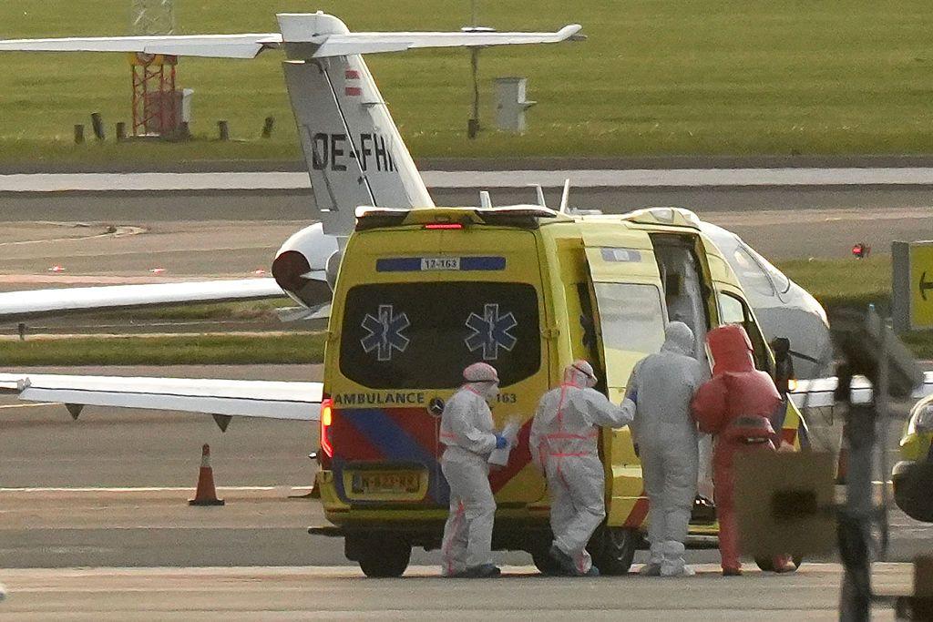Personas con trajes especiales evac&uacute;an a un paciente en un aeropuerto.
