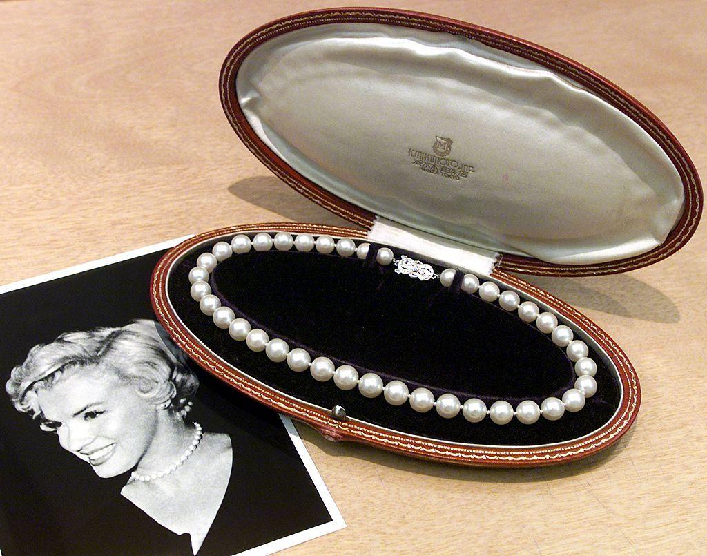 Collar de perlas en un estuche junto a una foto de Marilyn Monroe en la que luce ese mismo collar