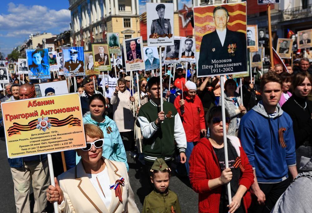 Una multitud de personas desfila por una calle portando pancartas con im&aacute;genes de soldados y veteranos durante una marcha del "Regimiento Inmortal" en Vladivostok.