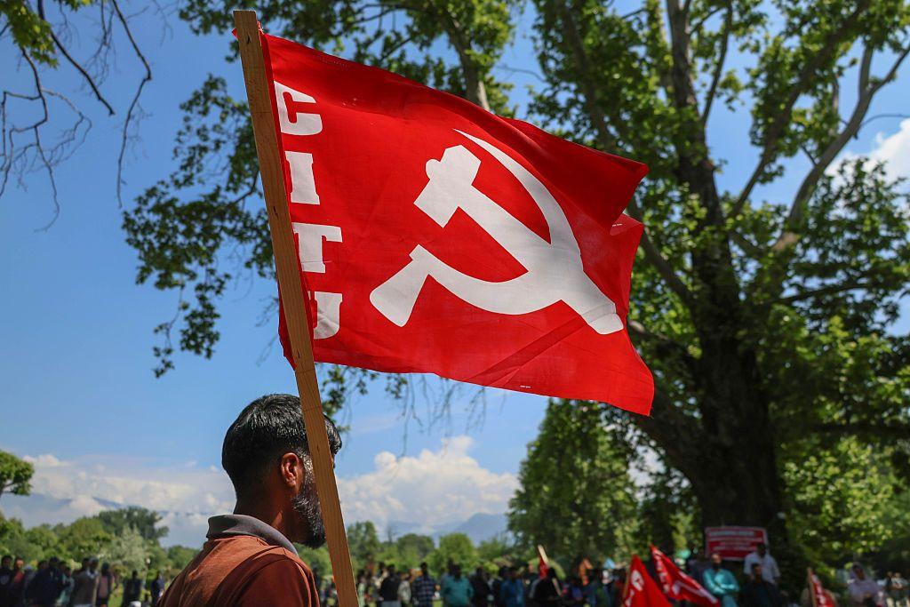 Un trabajador subcontratado sostiene la bandera del Partido Comunista de la India (Marxista) (CPI-M) durante una manifestaci&oacute;n