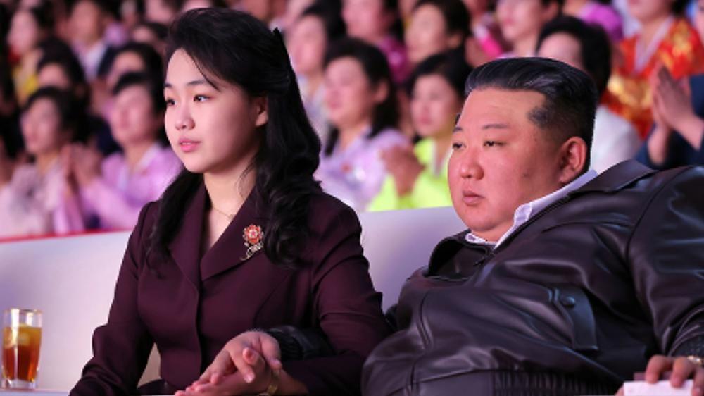 Kim Ju Ae y Kim Jong Un, sentados presenciando un evento en un gimnasio.