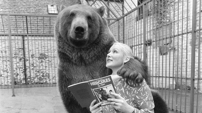 Maggie ley&eacute;ndole un libro a H&eacute;rcules. 
