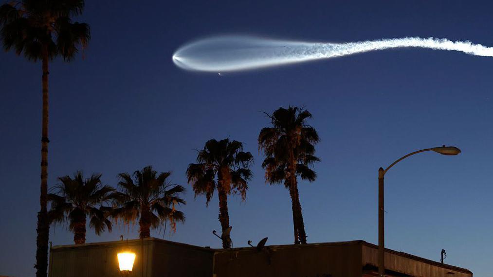 Una estela blanca dejada en el cielo oscuro por un cohete que lleva uno de los sat&eacute;litles de Starlink.