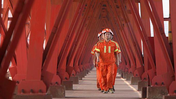 Varios trabajadores vestidos de naranja en una planta petrolifera de China