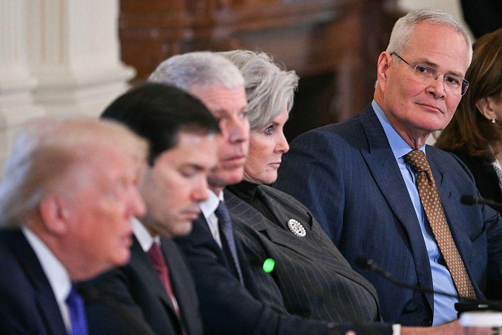 Donald Trump hablando y a lo lejos lo ve el presidente de ExxonMobil,  Darren Wood