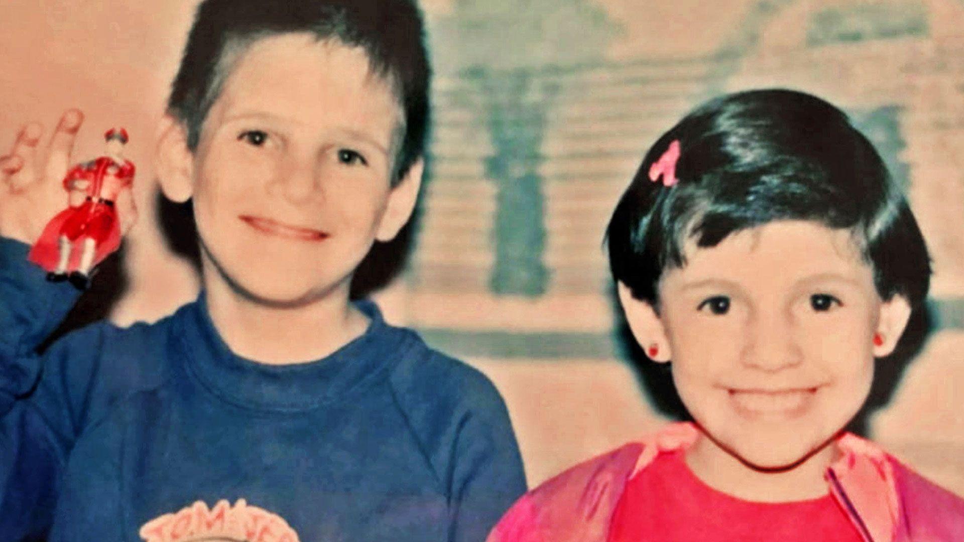 Un ni&ntilde;o con una camiseta azul y una ni&ntilde;a con una camiseta rosa, ambos de cabello oscuro, sonr&iacute;en a la c&aacute;mara; el ni&ntilde;o sostiene una figura de juguete.