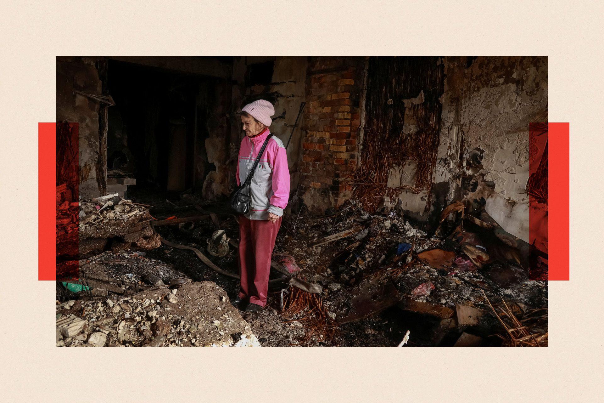 Una mujer vestida de rosa inspecciona las ruinas tras un ataque ruso en Ucrania.