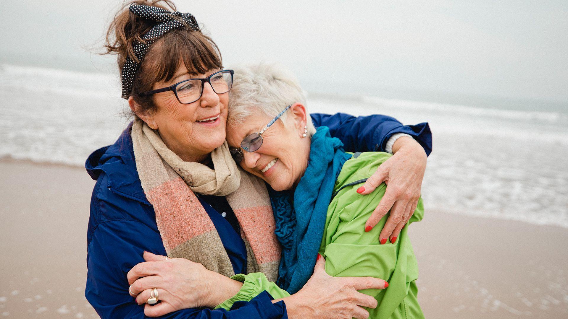 Dos mujeres se abrazan en la playa.