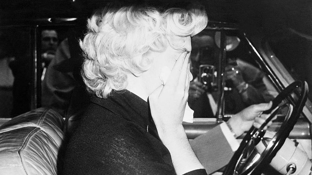 Marilyn Monroe en un auto se lleva las manos a la cara, con tristeza, tras la separaci&oacute;n de Joe DiMaggio