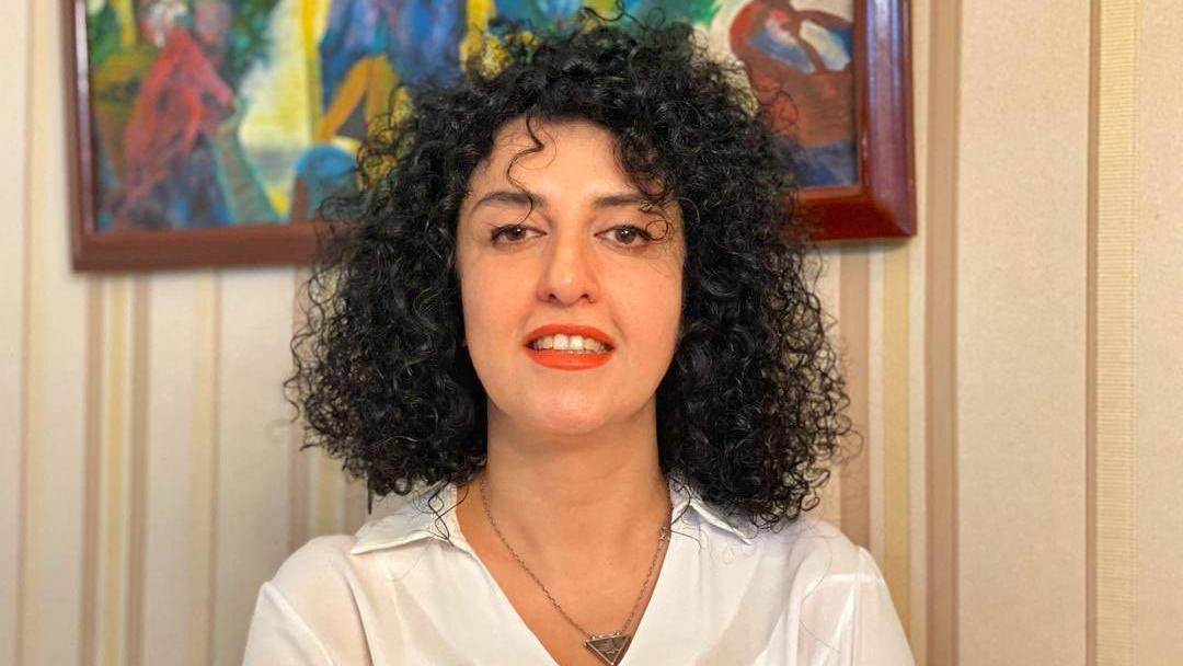 Narges Mohammadi sonr&iacute;e en esta foto de folleto sin fecha. Tiene el pelo negro rizado y lleva una camisa blanca, un collar en forma de tri&aacute;ngulo y l&aacute;piz labial rojo.