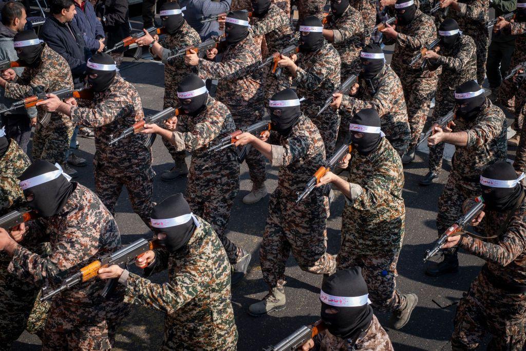 Varios miembros del CGRI, vestidos con indumentaria militar y pasamonta&ntilde;as negros, apuntan con sus armas durante un ejercicio.