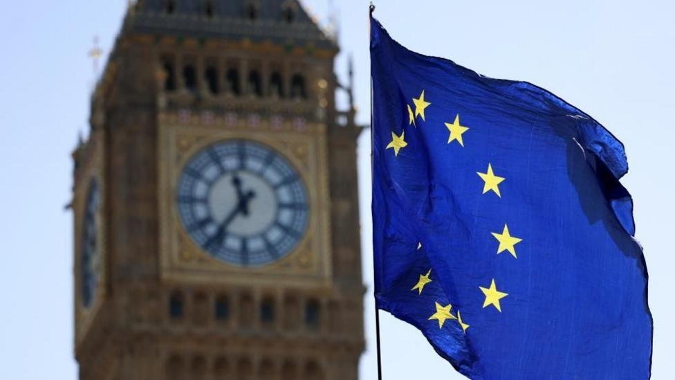 El Big Ben junto a una bandera de la Uni&oacute;n Europea
