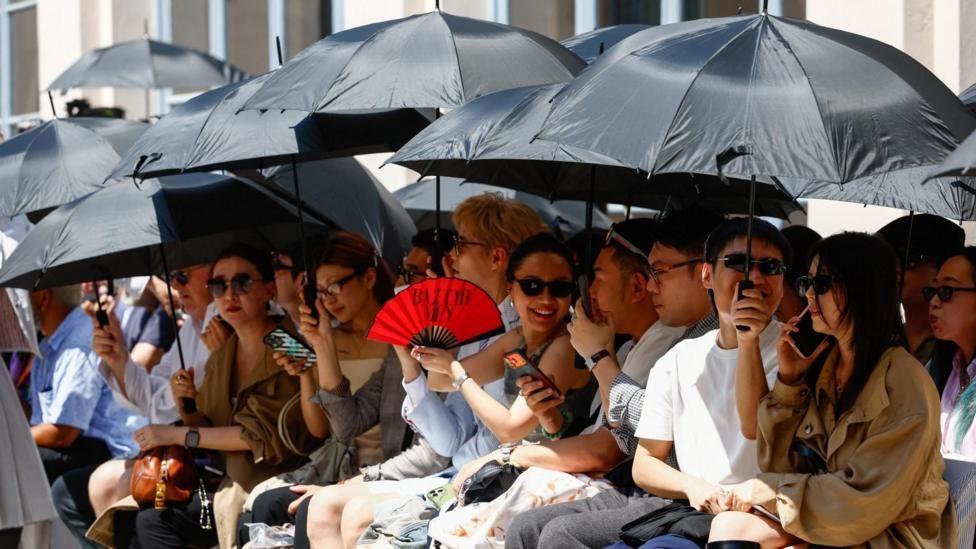 Personas protegi&eacute;ndose del sol con sombrillas durante la Semana de la Moda de Mil&aacute;n  