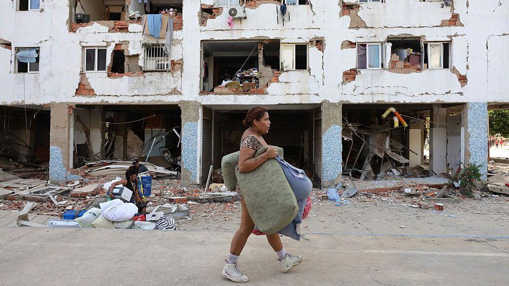 Una mujer pasa por delante de un edificio que sufri&oacute; extensos da&ntilde;os. 