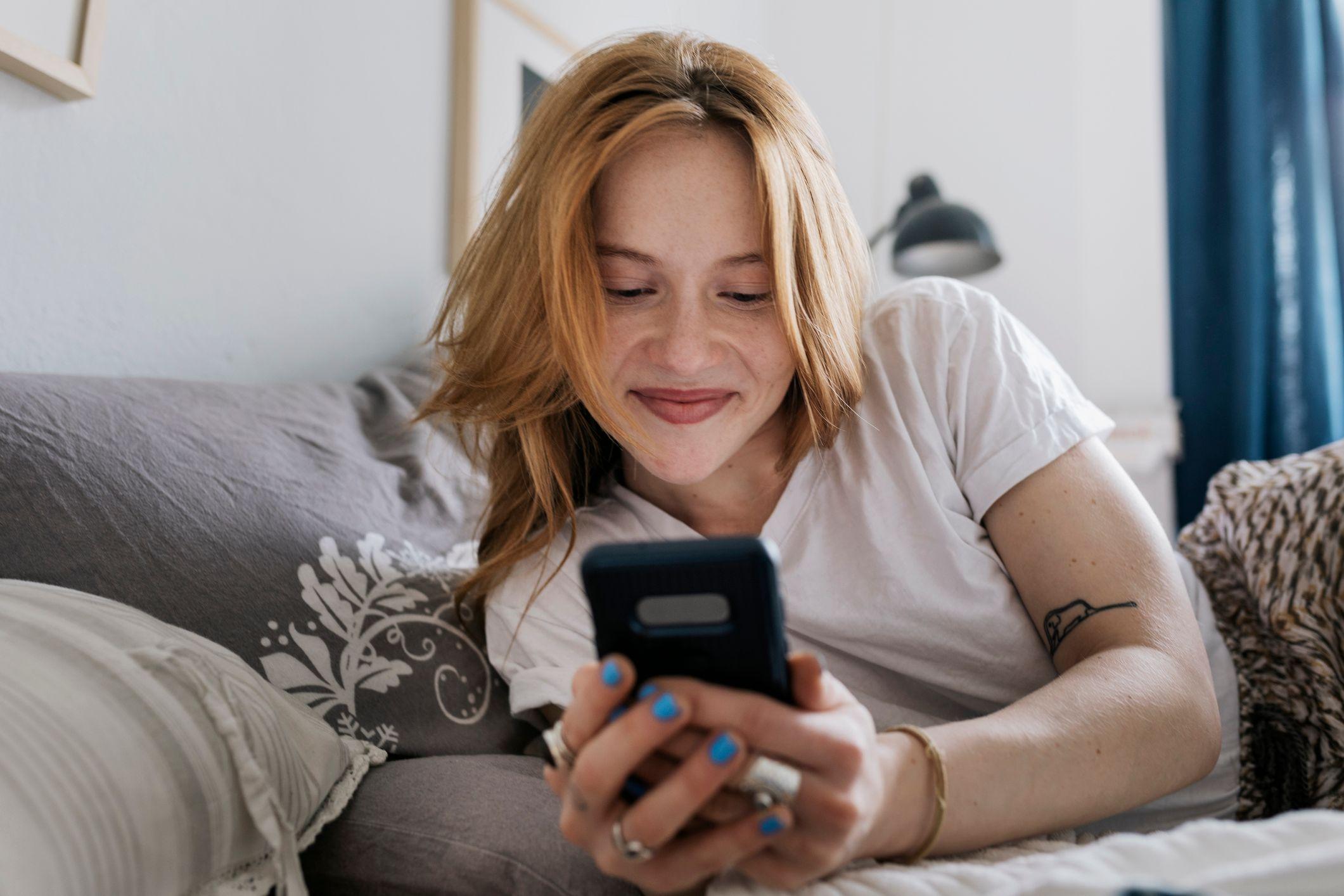 Mujer mirando el tel&eacute;fono sonriendo