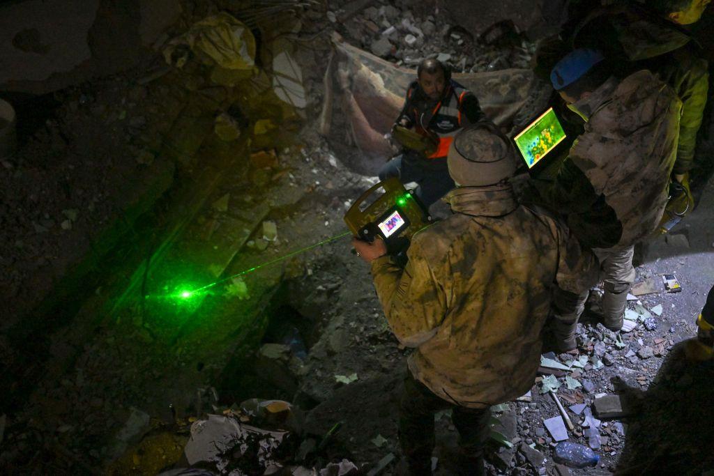 Un rescatista con sombrero y abrigo utiliza equipo de imagen t&eacute;rmica en el lugar de un terremoto en Turqu&iacute;a.
