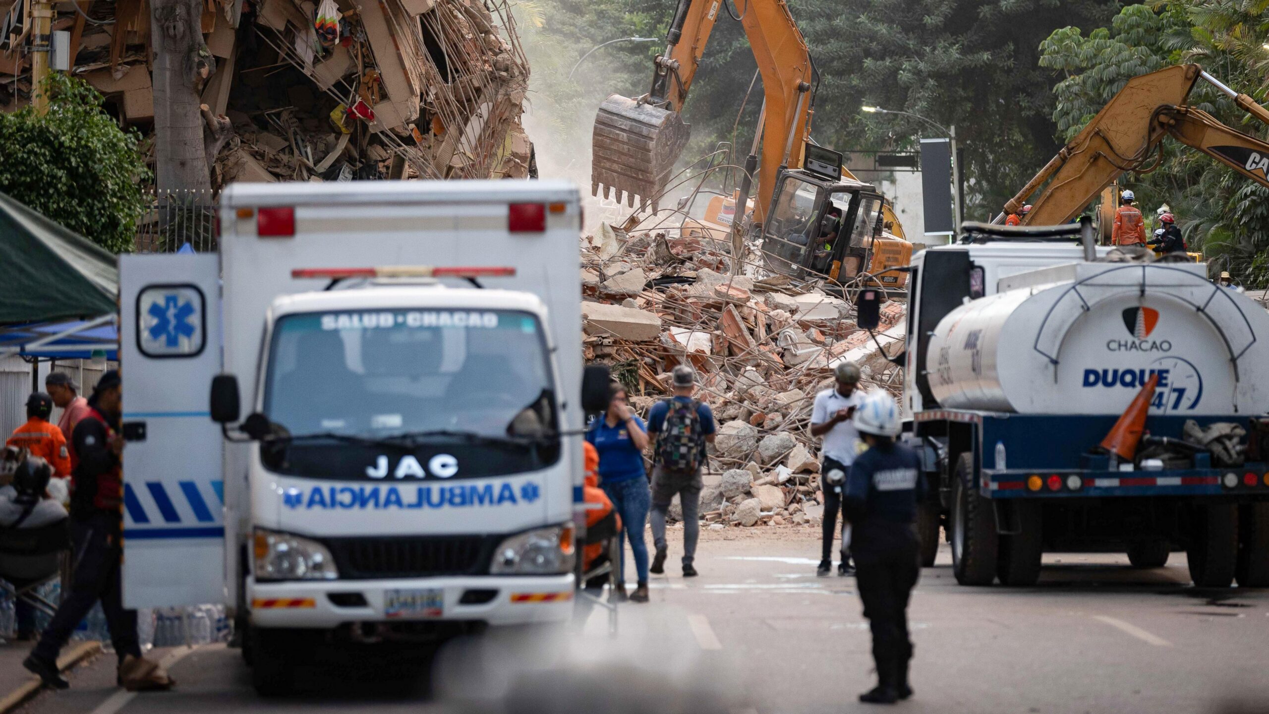 Equipos de rescate y maquinaria pesada trabajan sobre los escombros de varios edificios en una zona de Caracas.