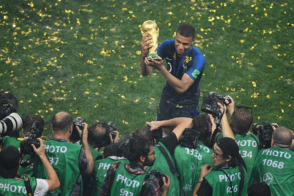 Mbapp&eacute; sostiene la copa del mundo mientras los fot&oacute;grafos disparan sus c&aacute;maras.