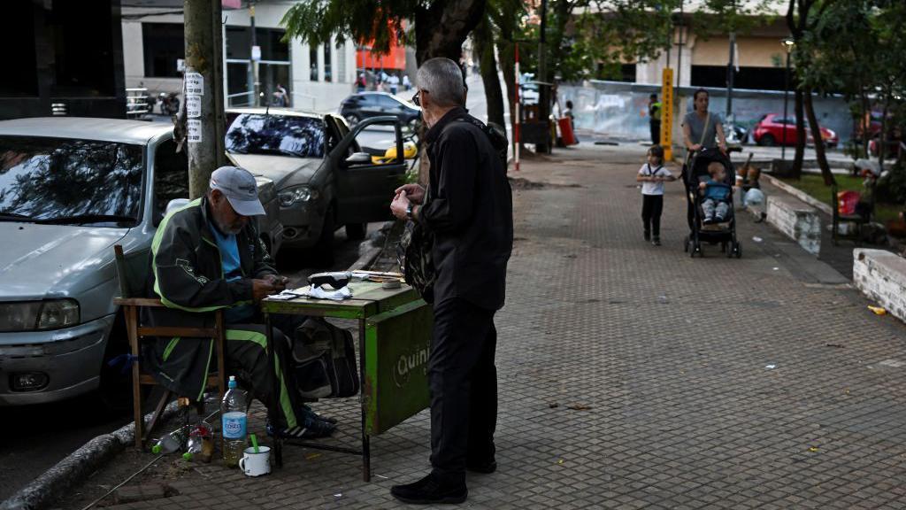 Un hombre cuenta billetes de guaran&iacute;es en una calle de Asunci&oacute;n