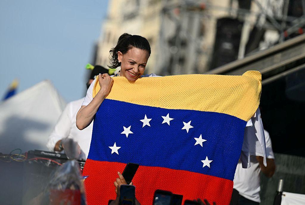 La l&iacute;der opositora venezolana Mar&iacute;a Corina Machado sostiene una bandera de Venezuela mientras sus partidarios se re&uacute;nen en la Puerta del Sol de Madrid el 18 de abril de 2026.
