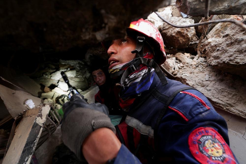 Un bombero, que lleva casco y un abrigo resistente, sostiene una peque&ntilde;a c&aacute;mara de b&uacute;squeda en la mano mientras busca sobrevivientes del terremoto.