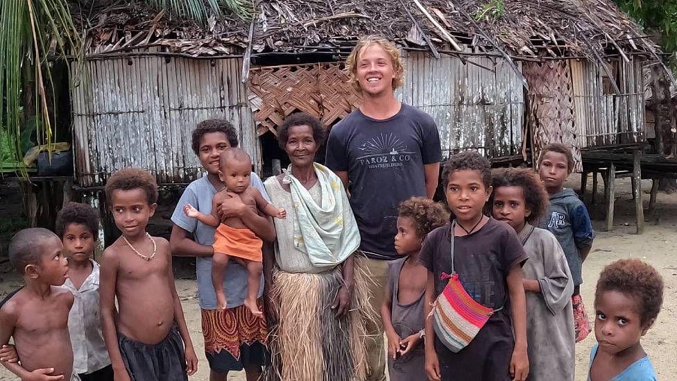 Robinson rodeado por una mujer y ni&ntilde;os en la isla de Penrhyn